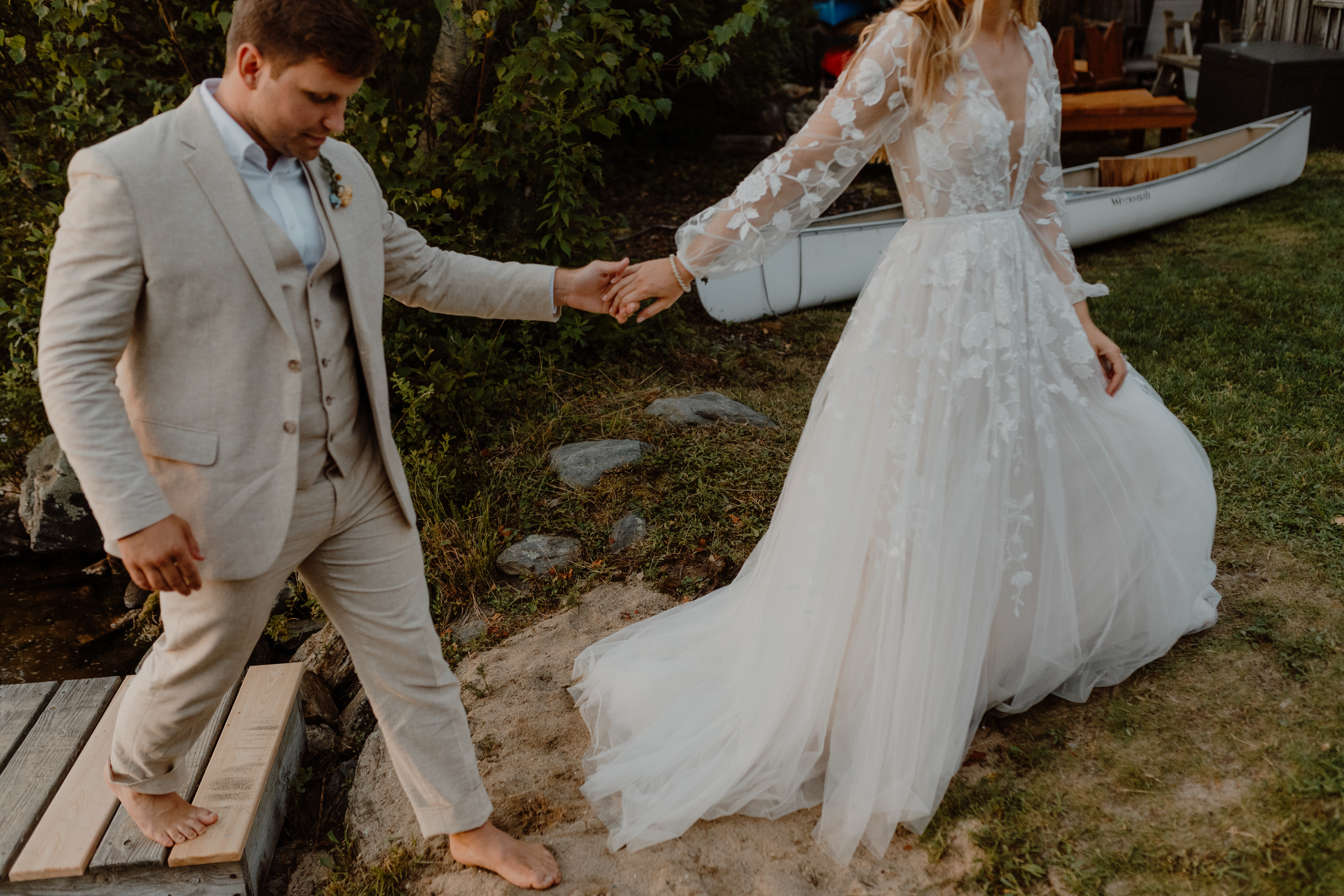 bride and groom holding hands and walking on dock