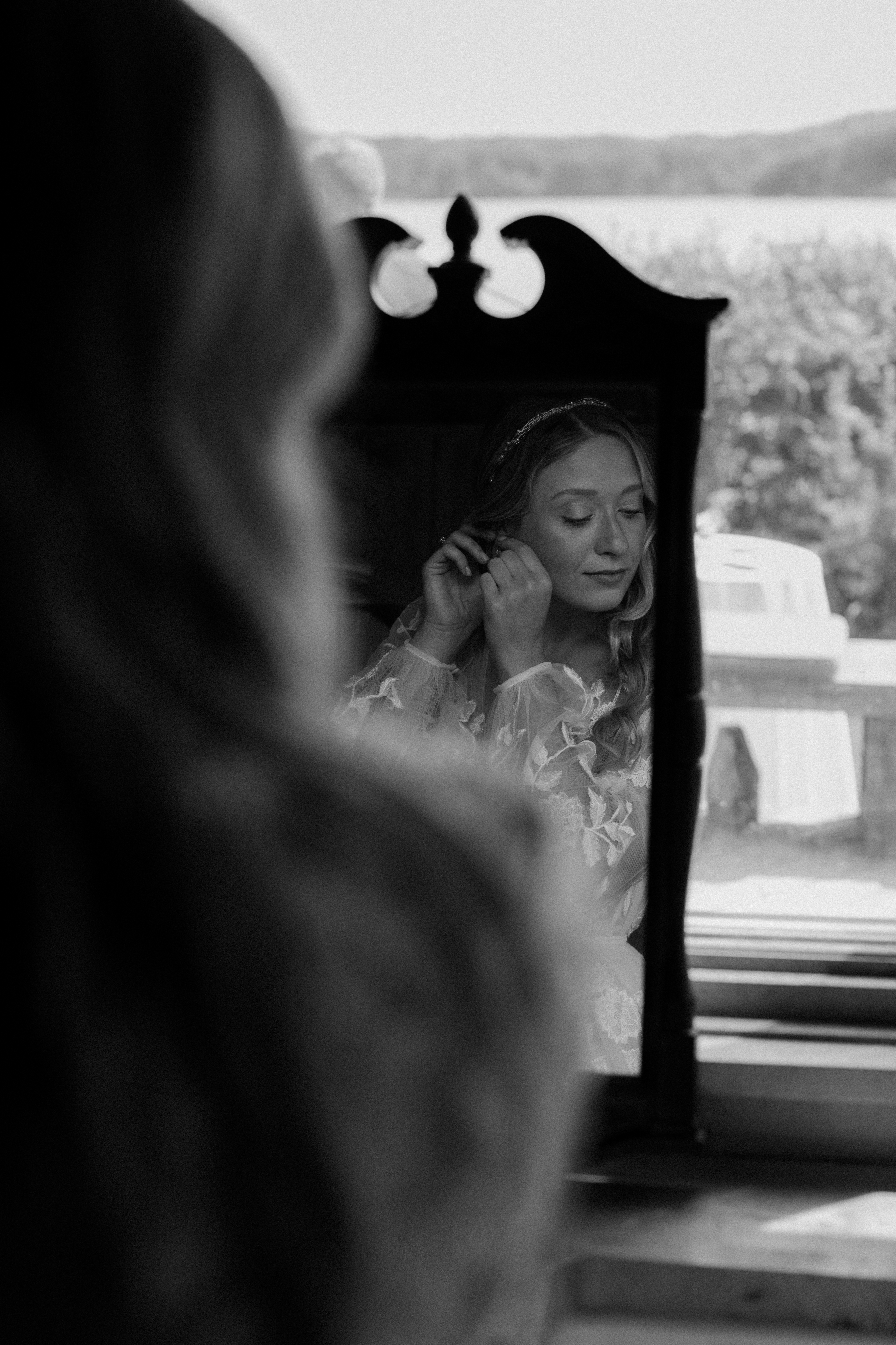 bride putting on earrings in antique mirror