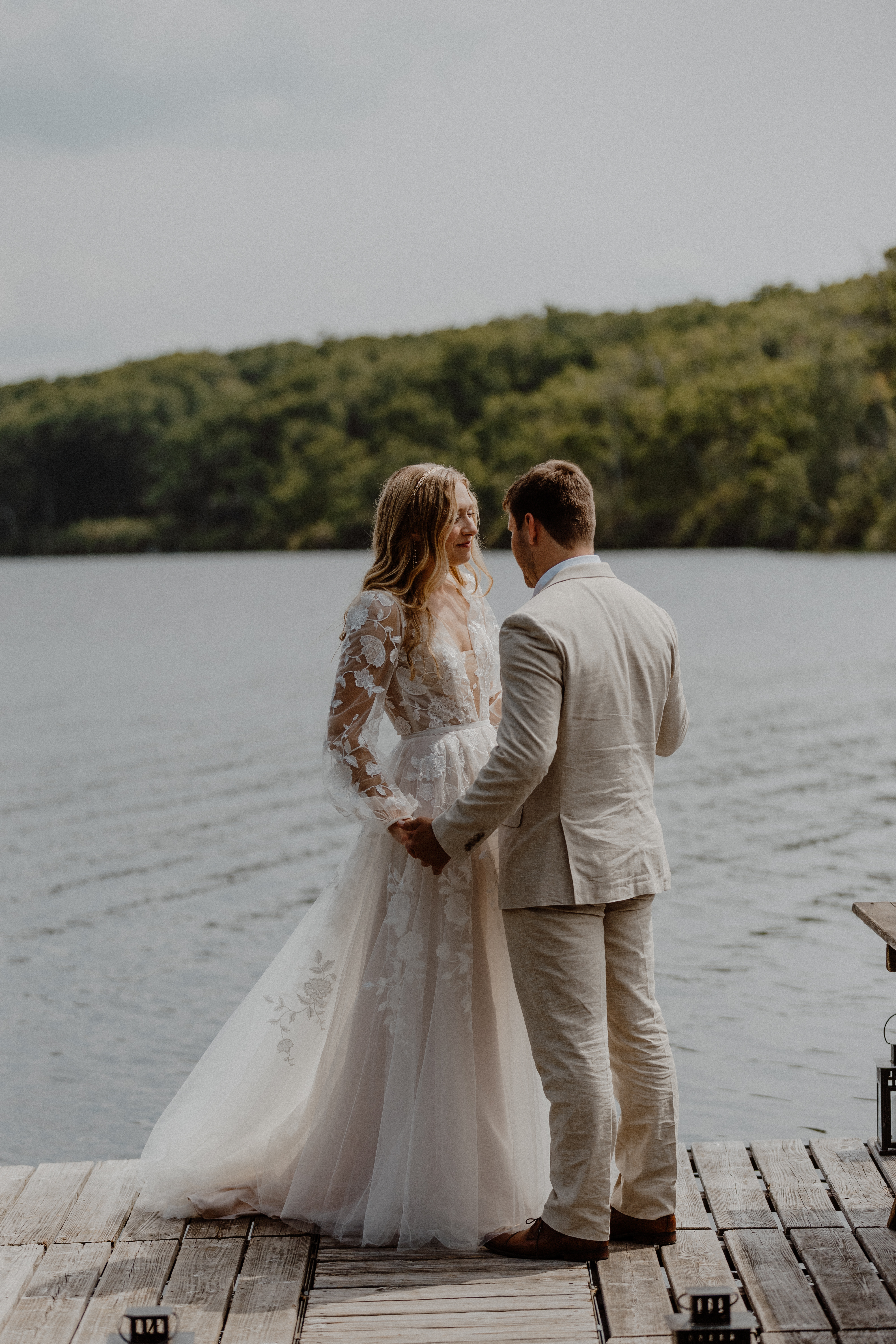 bride and groom standing next to lake