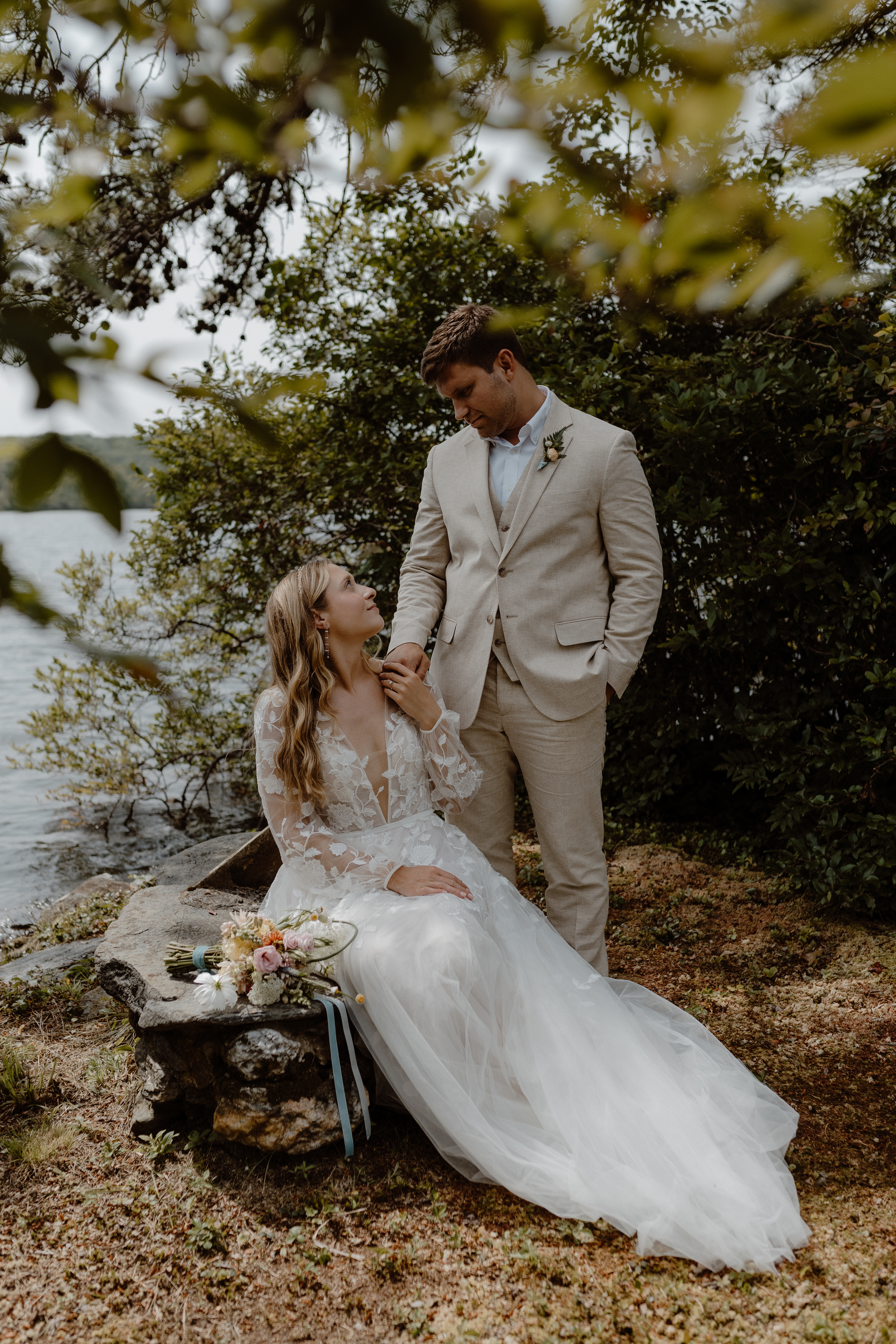 couple sitting on rock in front of pond