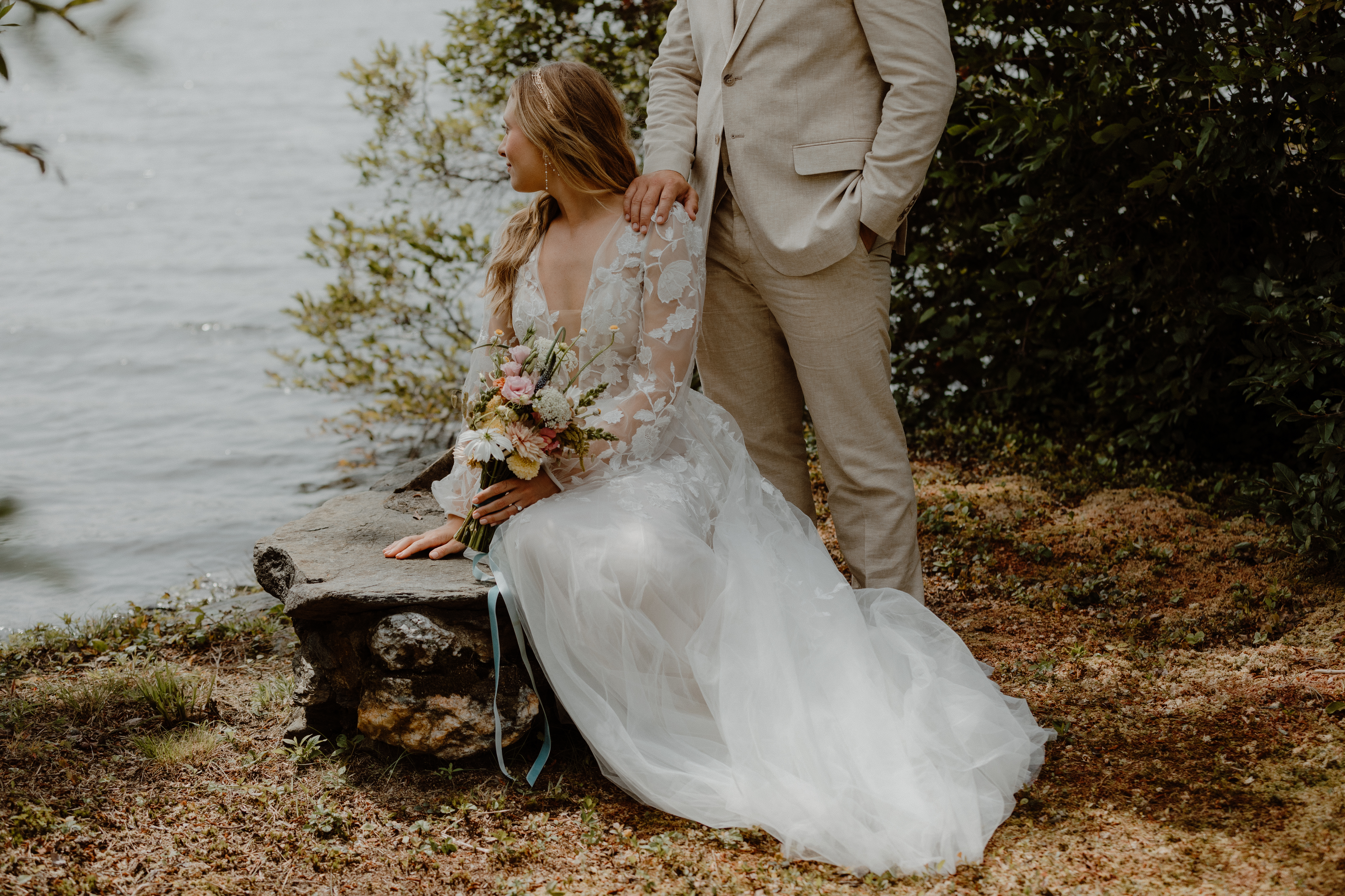 bride sitting on rock in front of groom