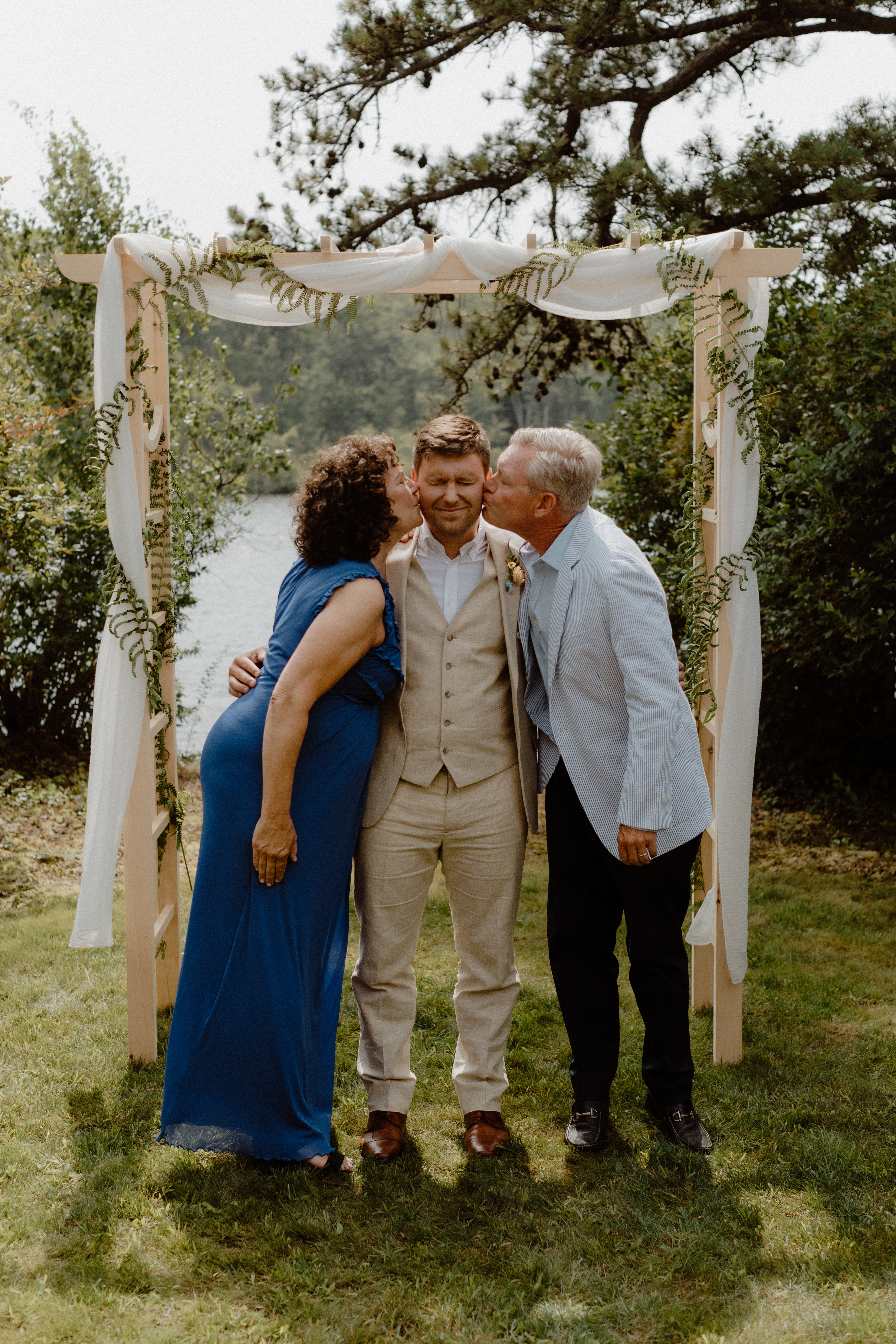 groom's parents kissing him on the cheek
