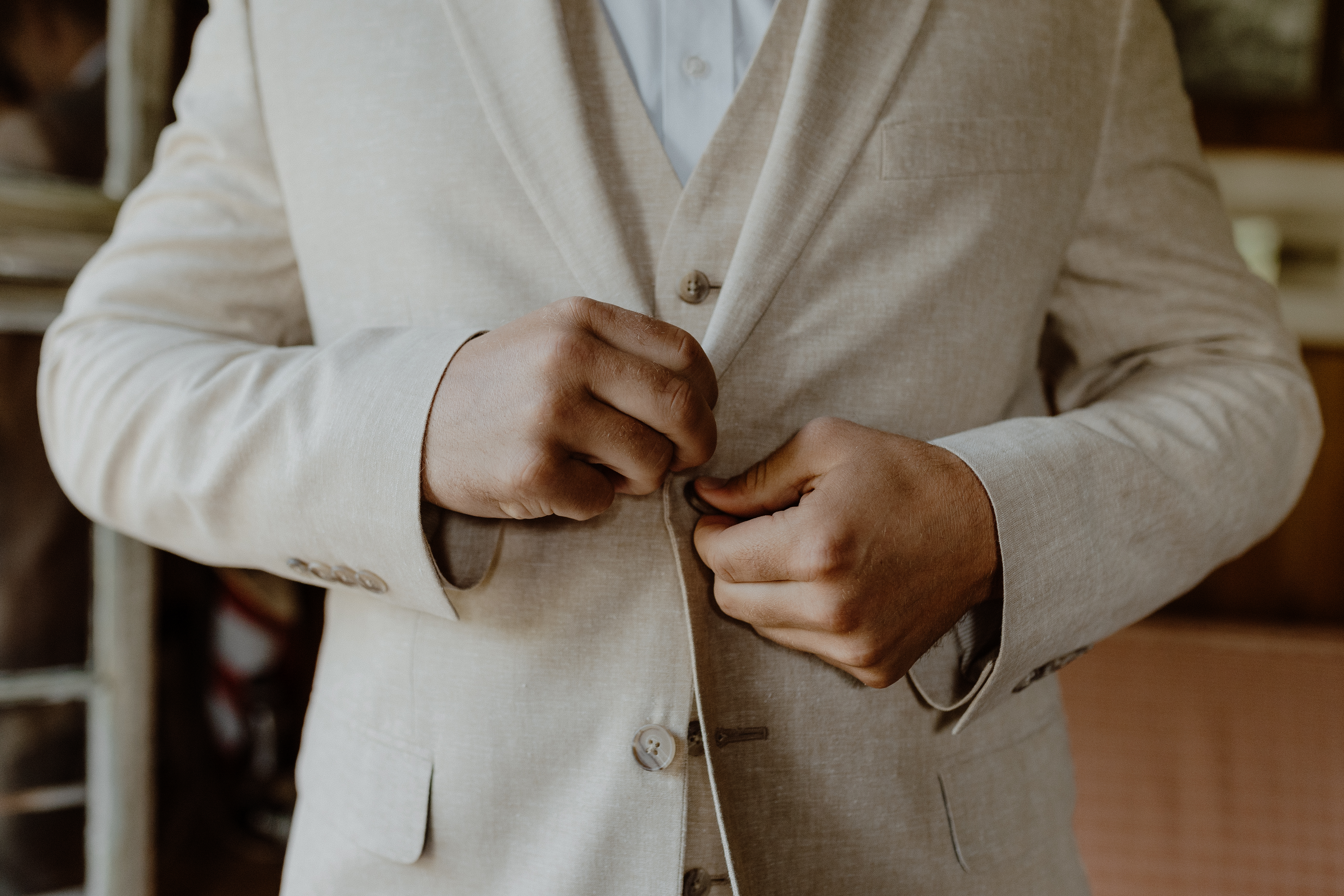 groom buttoning suit jacket