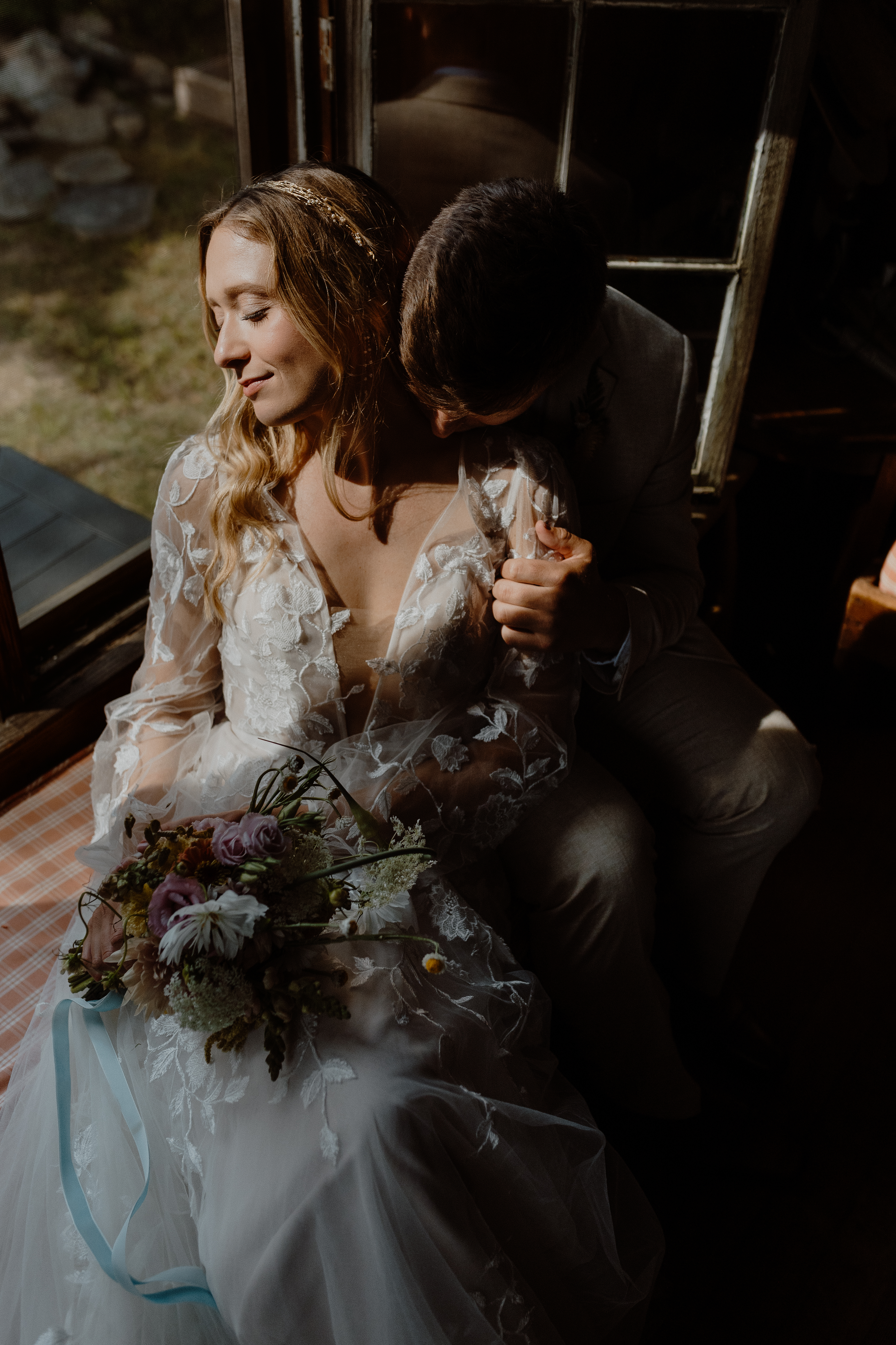 groom embracing bride on window seat in cabin