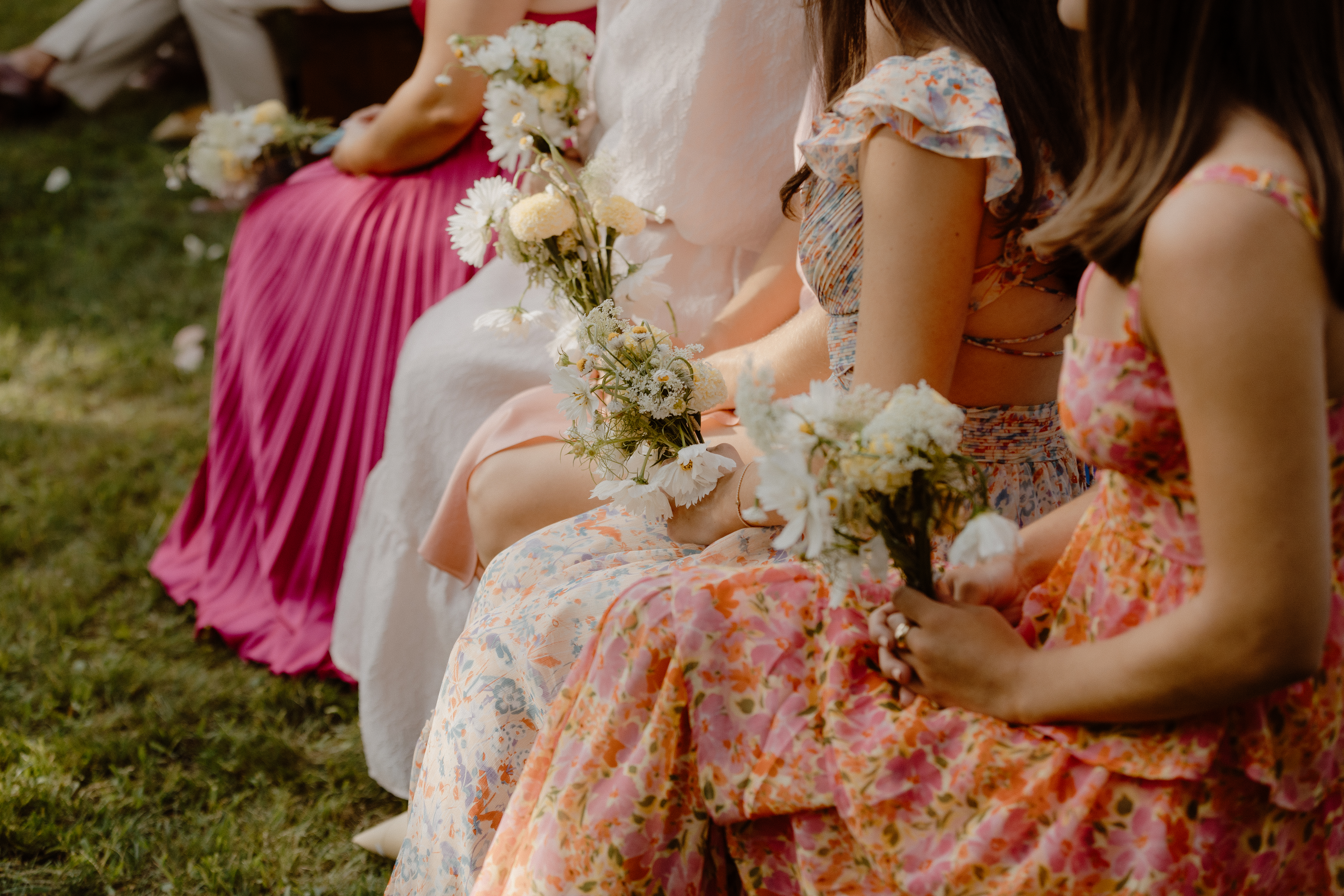 bridesmaids with mix matched summer dresses holding white bouquets