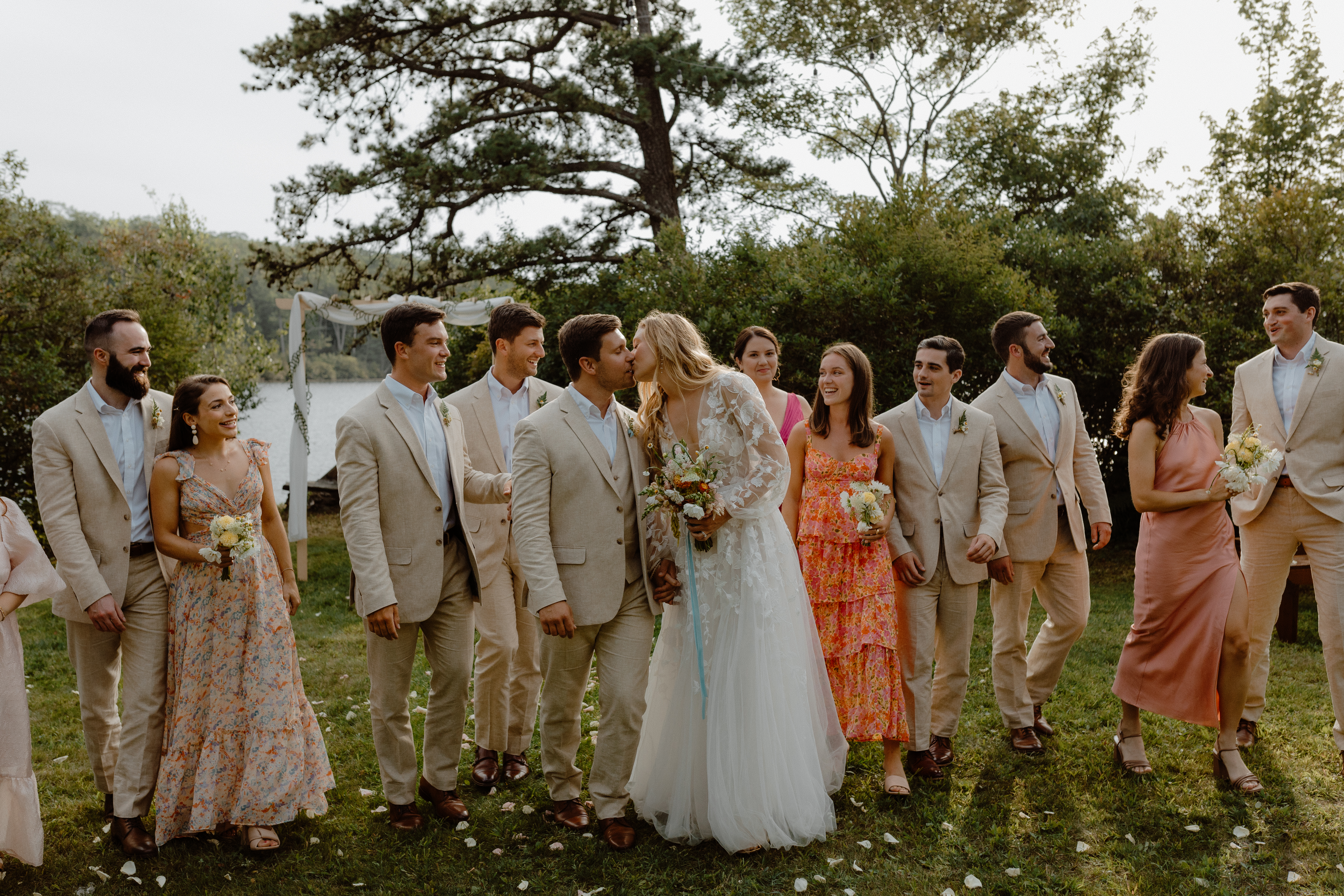 couple kissing surrounded by wedding party