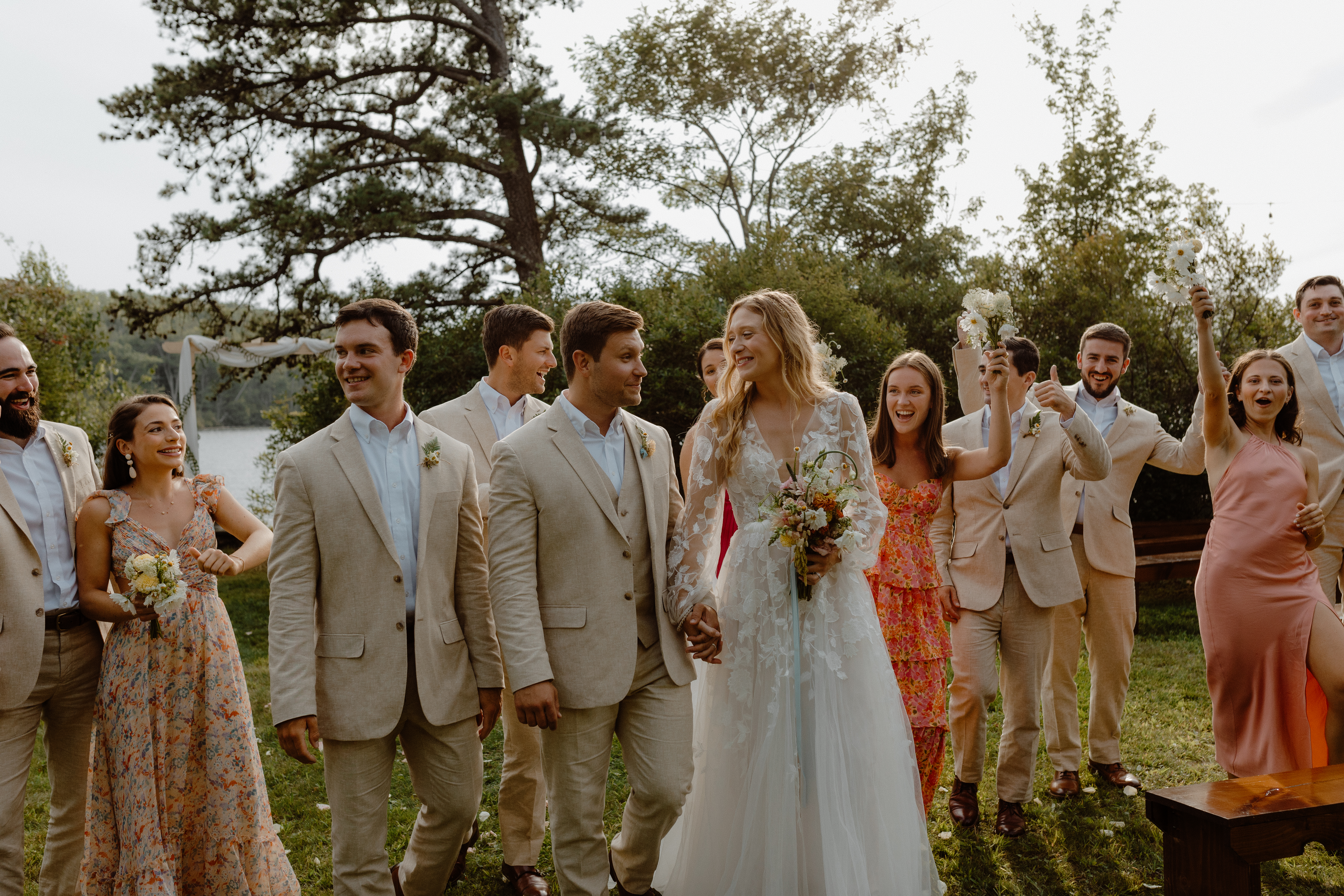 bride and groom surrounded by wedding party cheering and laughing
