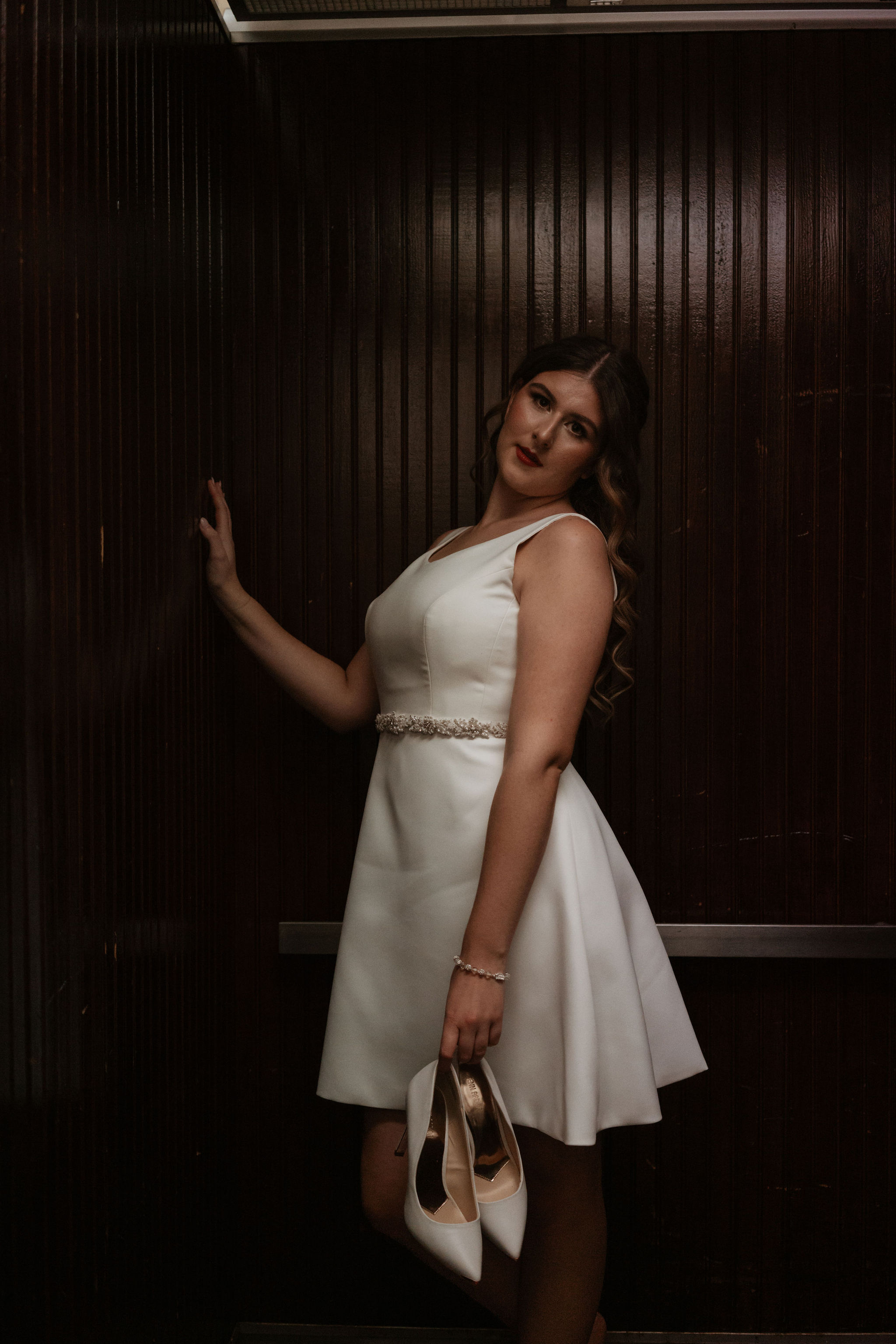 bride holding heels in elevator