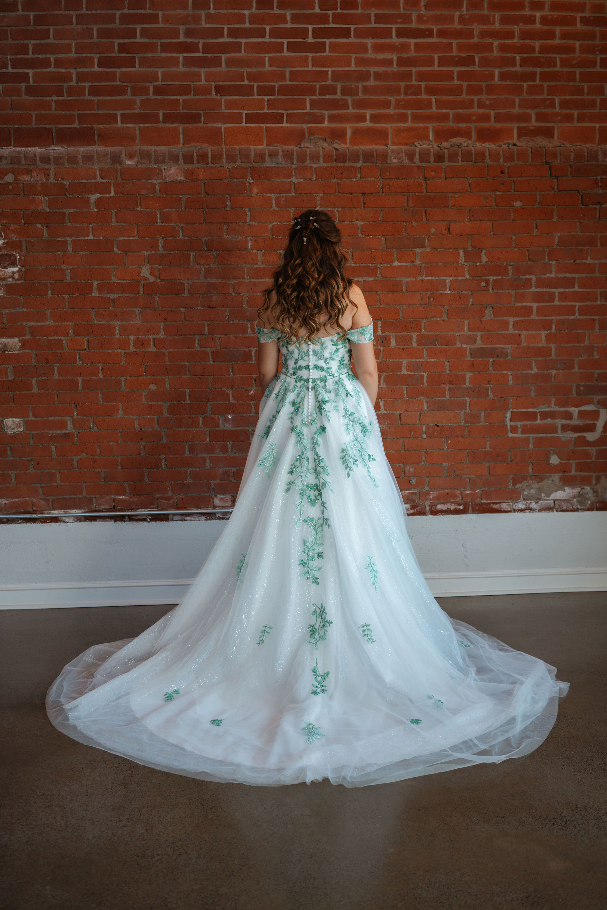 bride showing her hair and greenery wedding dress details