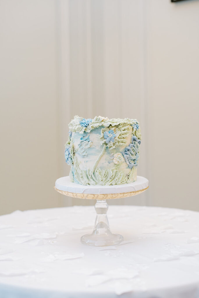 Eolia Mansion - Jennifer Conti Photography - small 6" cake on a clear cake server, the cake is embossed in buttercream in light greens and blues giving it a 3D textured look 