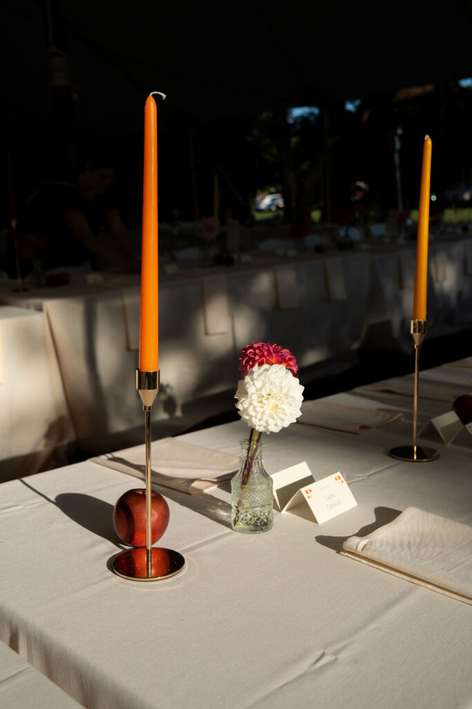 Private Estate Tented Wedding ~ Lyme, CT - Gambo Photo Co. - Ivory linen tables set with ivory waterfall napkins, an array of colored candles in gold tapers holders adorned with apples and flowers in bud vases and simple tent escort cards. 